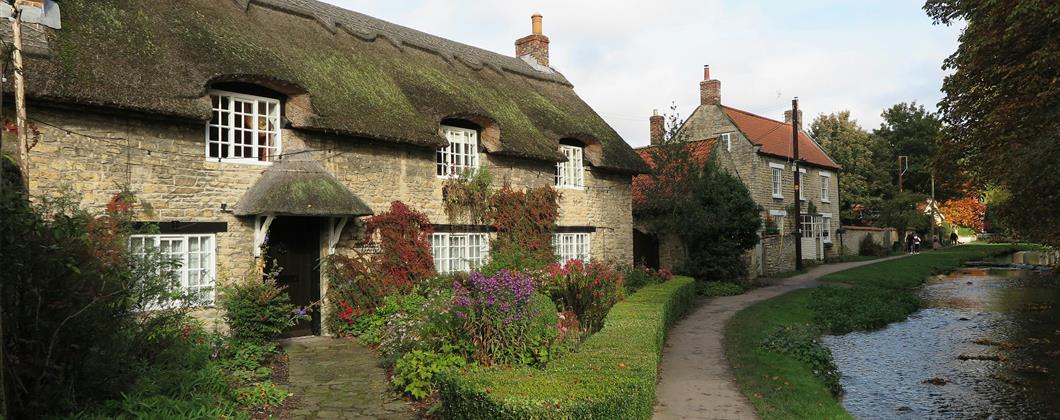 Outside of thatched roof cottage in a village. 